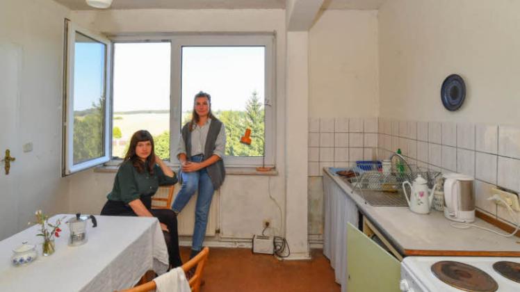 Larissa Rosa Lackner (l) und Theresa Pommerenke sitzen in ihrer Plattenbauküche.  
