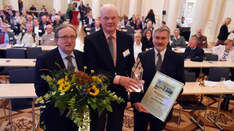 Unternehmerverbandschef Rolf Paukstat (l.) und Stellvertreter Detlef Els übergeben die Auszeichnung an Norbert Rethmann (M.).  