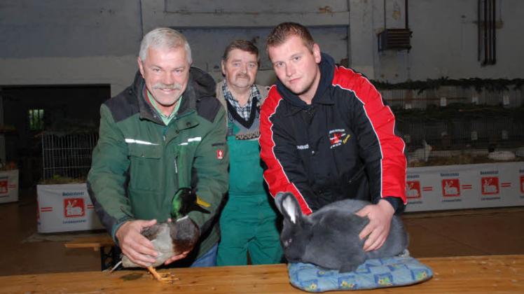 Preisträger und Tombolapreis: Christopher Kröplin (r.) mit einem Blauer Wiener, mit dem er Vereinsmeister wurde. Bützows Vereinschef Norbert Bissa (l.) mit dem Geschenk der Rassegeflügelzüchter. Im Hintergrund Kreisvorsitzender Bernd Buddenhagen.  