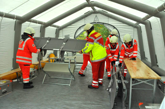 Das Behandlungszelt ist errichtet. Ein Generatorgebläse hält den Druck im Stützkorsett konstant. Helfer statten es jetzt mit dem notwendigen Einrichtungsgerät aus. Das Behandlungszelt ist errichtet. Ein Generatorgebläse hält den Druck im Stützkorsett konstant. Helfer statten es jetzt mit dem notwendigen Einrichtungsgerät aus.