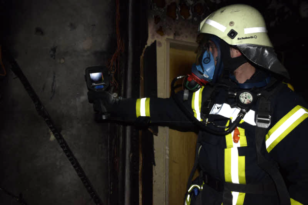 Ein Feuerwehrmann der Hagenower Wehr kontrolliert im Treppenaufgang die Temperatur des Betons. 