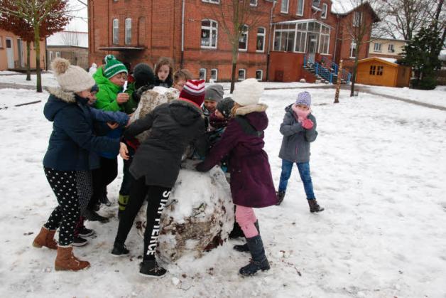 Mit vereinten Kräften bauen die Schüler der Grundschule Roggendorf Schneemänner aus dem nassen Schnee.  