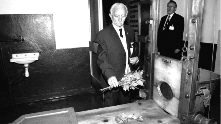 Der ehemalige Häftling Hermann Baade legt 1995 einen Strauß Rosen auf das Fallbeil im Hinrichtungsraum des früheren Zuchthauses Brandenburg-Görden.