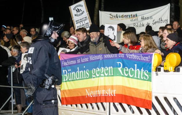 Demonstranten in Aukrug: Sie halten ein Transparent mit der Aufschrift „Faschismus ist keine Meinung, sondern ein Verbrechen. Bündnis gegen Rechts Neumünster“ über die Polizei-Absperrung.