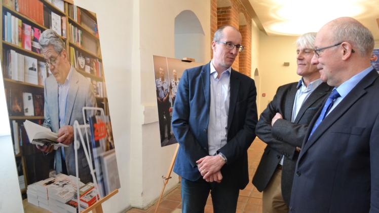 Bei der Ausstellungseröffnung im Rathaus sehen sich der Hamburger Fotograf Christian Irrgang (M.), Oberbürgermeister Roland Methling (r.) und Bundestagsmitglied Peter Stein (CDU) die Bilder an.  