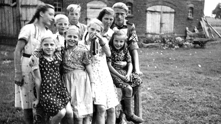 Ruth Jakuszeit (vorn, 2.v.l.) 1940 an ihrem 12. Geburtstag mit Freunden vor dem Elternhaus. Der steinerne Brunnen ist das Einzige, was von der Bauernstelle geblieben ist.