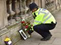 Ein Polizist legt Blumen an einem Foto in der Nähe des britischen Parlament in London nieder. 