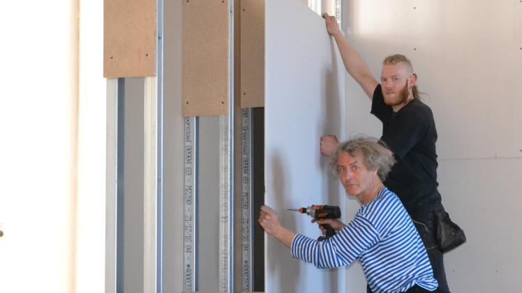 Stefan Nestler (vorn) und Tobias Hees von der Rostocker Firma „Wolkenbank Kunst + Räume“ bauen derzeit ein Raum-in-Raum-System im Güstrower Schloss auf. Hier werden später die Cranach-Werke hängen.  