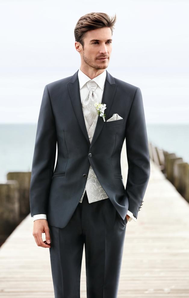 Eine etwas breitere Krawatte, der Plastron, und ein Anstecksträußchen, die Boutonnière, verleihen dem Anzug Festlichkeit.  