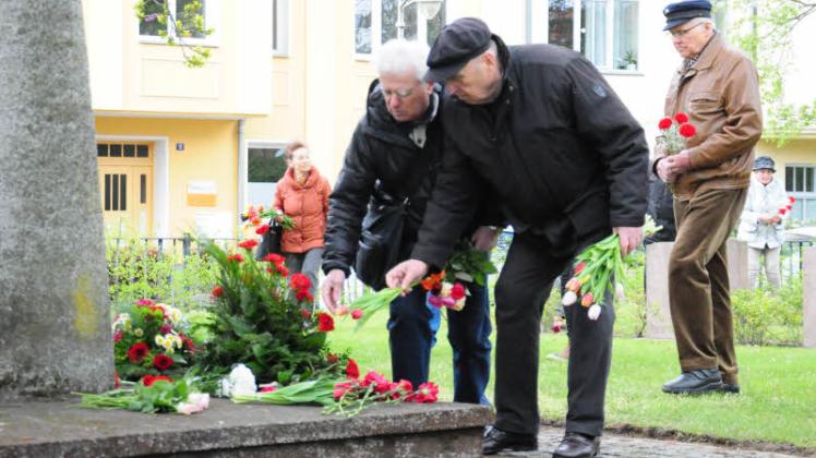 Anlässlich des Tags der Befreiung legen Filler Roma (l.) und Mihnovschi David Blumen auf die Gräber auf dem Ehrenfriedhof am Rostocker Puschkinplatz.