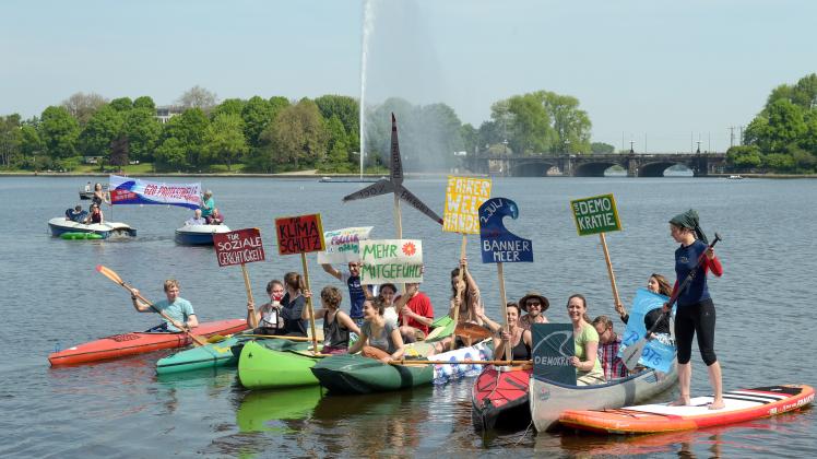 Aktivisten paddeln am Donnerstag in Hamburg auf der Binnenalster während sie Schilder zum Protest gegen den G20 Gipfel in die Höhe halten. Die Aktion steht unter dem Motto „Warmpaddeln für die G20 Protestwelle“, die am 2. Juli in Hamburg stattfinden soll.