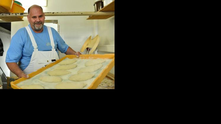 Bäcker Holger Schüren  hält in Nuthetal ein Brett mit frisch gemachten Baguettes in den Händen.  