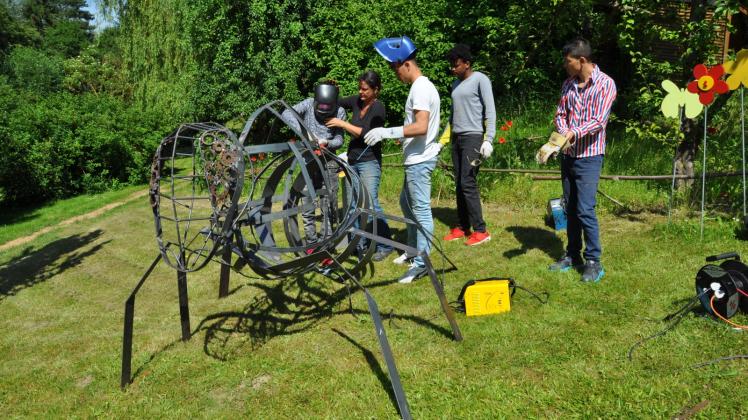 Metallkünstlerin Takwe Kaenders (2.v.l.) vom Rothener Hof führt das Projekt „Biene schweißt zusammen“ in Lütt Acker Sternberg mit vier jungen Leuten aus Afghanistan und Eritrea durch, die vom Verein Dialog + Action betreut werden.  Fotos: Rüdiger Rump 