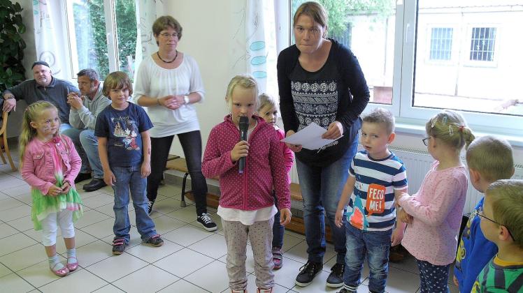 Übungen mit dem Mikro: Die Kinder begrüßen die Gäste. Links hinten Leiterin Heike Zeppelin, rechts zwischen den Kindern Erzieherin Janine Hoeft