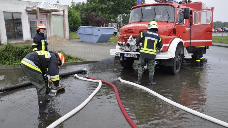 Kameraden der Feuerwehr pumpen die überflutete Straße zum Quitzower Gewerbegebiet ab.  