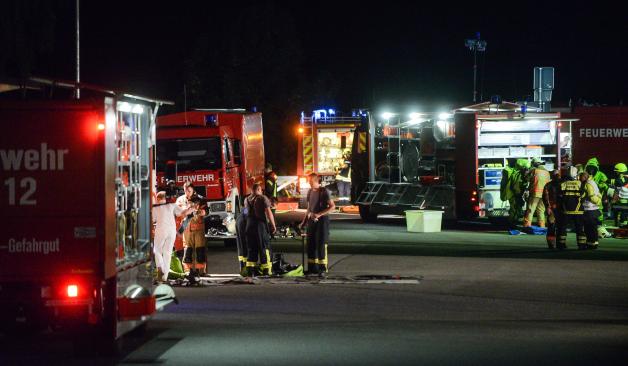 Einsatzkräfte der Feuerwehr in Schutzanzügen sind auf der Autobahn 24 bei Walsleben (Brandenburg) im Einsatz. Ein leckgeschlagener Gefahrguttransporter hat einen Großeinsatz der Feuerwehr ausgelöst.