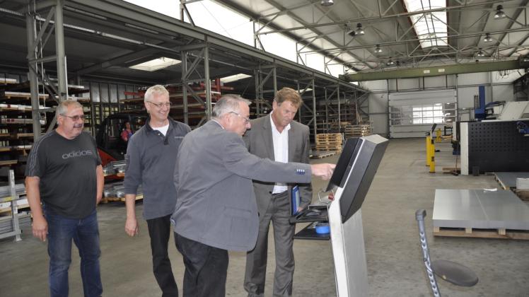 Geschäftsführer Hans-Detlef Jung erklärt Minister Christian Görke die Funktionsweise der Stanz-Nibbel-Maschine.  