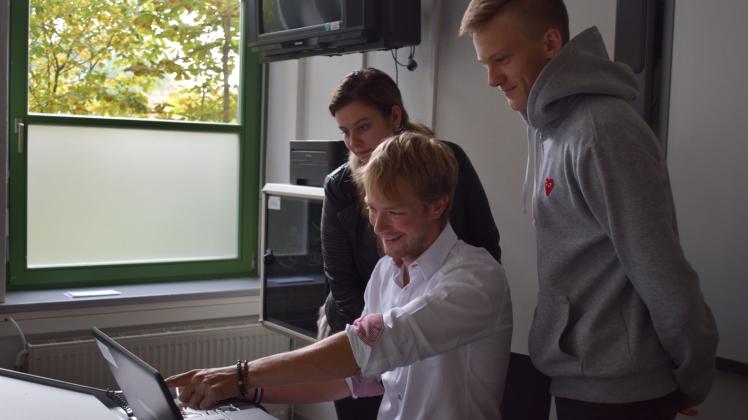 Lehrer Morten Jensen zeigt den Schülern Lilly Stricker und Yannick Doleczik den digitalen Stimmzettel. 