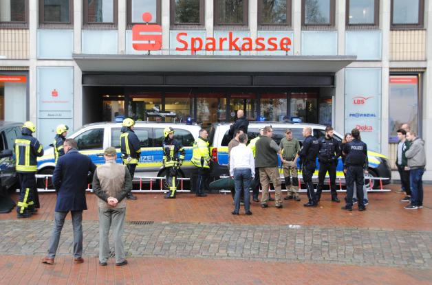Einsatzkräfte der Polizei und Feuerwehr haben den Eingang einer Sparkassen-Filiale mit ihren Fahrzeugen verbarrikadiert. 
