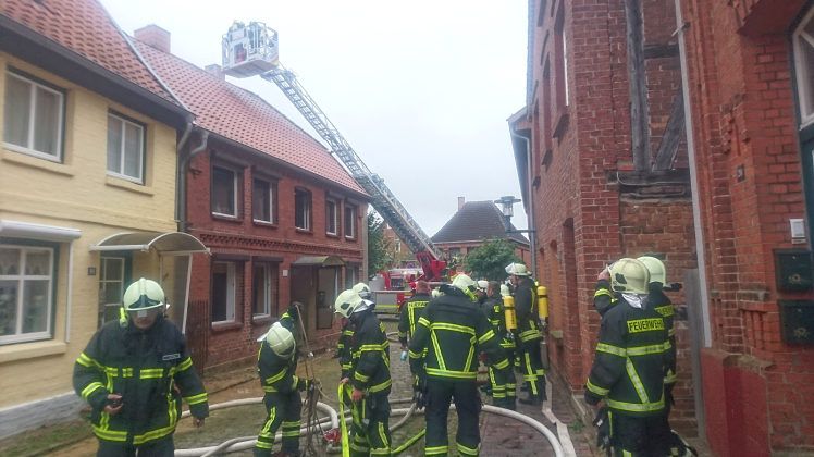 Kameraden der Lauenburger Feuerwehr untersuchen dank ihrer Drehleiter Glutherde im Dachgebälk des Einfamilienhauses. 