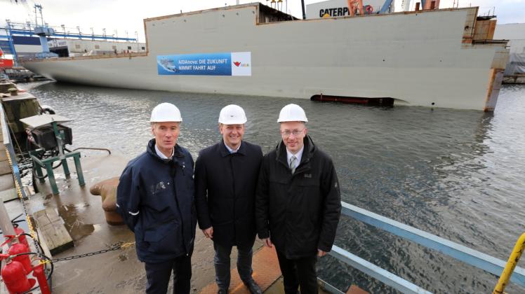 Auf der Neptun Werft stehen Geschäftsführer Raimon Strunck (v.l.n.r.), Aida-Präsident Felix Eichhorn und Energieminister Christian Pegel (SPD) vor dem Maschinenraumdodul. 