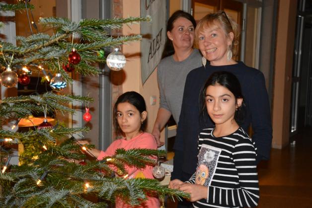Irina (11, r.) und ihre Schwester Natela schmücken den Weihnachtsbaum im Foyer des Mehrgenerationenhauses. Anne Bertram (hinten r.) und Stefanie Eden vom Zebef helfen dabei.