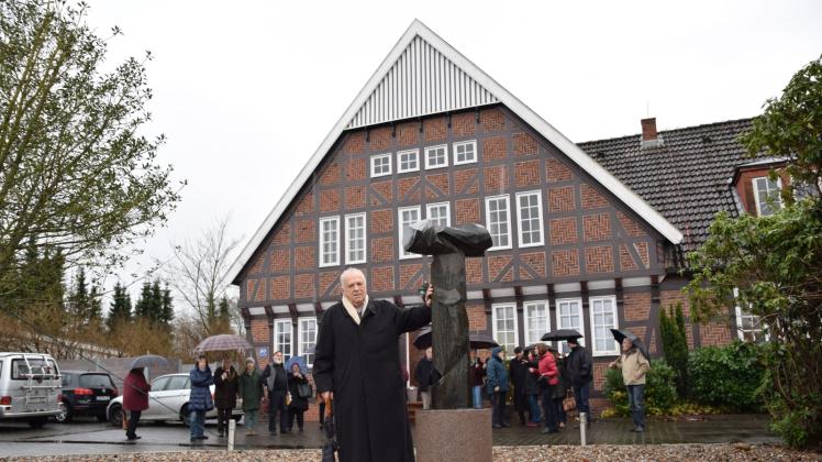 Bildhauer Manfred Sihle-Wissel präsentiert vor dem Fritz-Niemand-Haus an der Schleswiger Chaussee seine Bronze-Stele, die einen Hirtenstab darstellt.