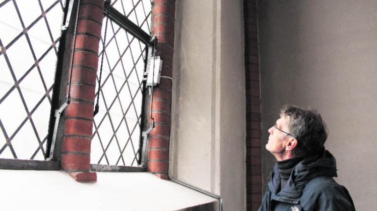 Pastor Erhard Graf vor den historischen Kirchenfenstern im Altarraum der Klein Wesenberger Kirche mit der neuen Belüftungstechnik. Kleines Foto oben rechts: Dieser ferngesteuerte Motor sorgt dafür, dass die Kirchenfenster je nach Bedarf auf- und zugehen. Fotos: schlüter 