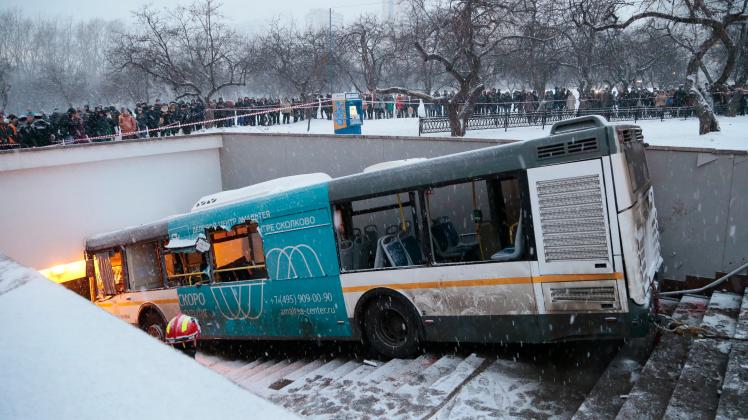 Rettungskräfte der Feuerwehr sind in Moskau neben einem zerstörten Linienbus, der die Treppe zu einer Unterführung hinunter fuhr, im Einsatz.
