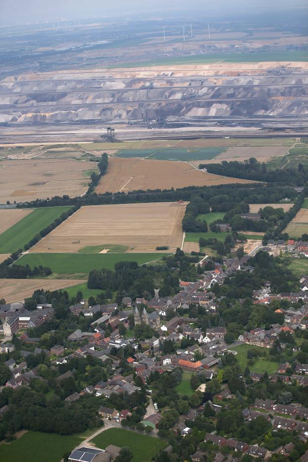 Die Luftaufnahme zeigt das Dorf Immerath fotografiert am 1. August 2014. Im Ortszentrum steht die Immerather Kirche. Im Hintergrund ist der Braunkohletagebau zu sehen. 