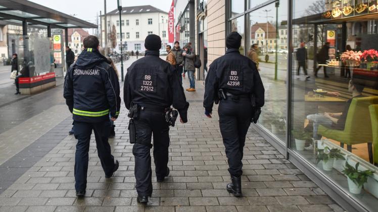Verstärkte Präsenz: Ein Mitarbeiter des Ordnungsamtes und zwei Beamte der Bereitschaftspolizei gehen auf Streife vor dem Einkaufszentrum Blechen Carré in Cottbus.