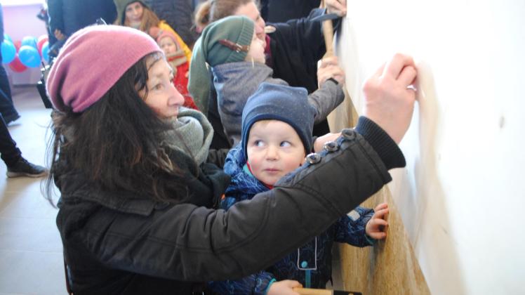 Einweihungsfeier mit Hammer und Nagel: Auch der dreijährige John und seine Tante Ute Senke verewigten sich an der Holzwand in der Werkstatt der Kita. 