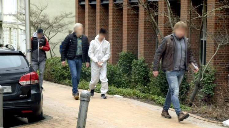 Zwei Kriminalbeamte bringen den Tatverdächtigen (weißer Schutzanzug) zum Haftrichter in Flensburg.