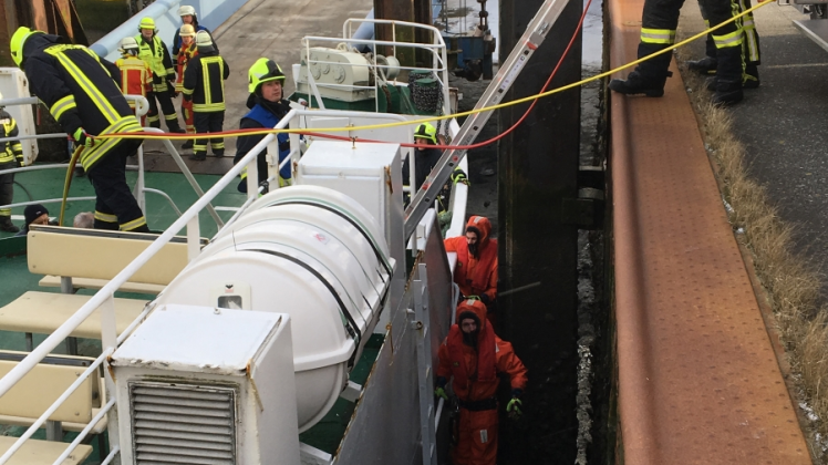 Im gemeinsamen Einsatz: Seenotretter (in Rot gekleidet) und Feuerwehrleute an der leckgeschlagenen Fähre „Insel Amrum“ im Hafen von Strucklahnungshörn. 