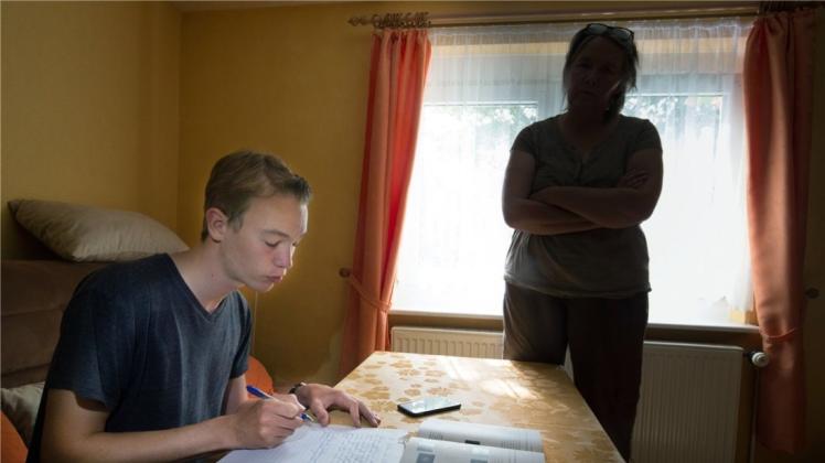 Ein Teenager (15) wird beim Lernen von seiner Mutter überwacht. In der Pubertät rutschen bei vielen Schülern die Noten in den Keller und die Eltern sorgen sich um die Zukunft ihrer Sprösslinge. Doch Strafen erzeugten bei Pubertierenden eher Widerstand. 