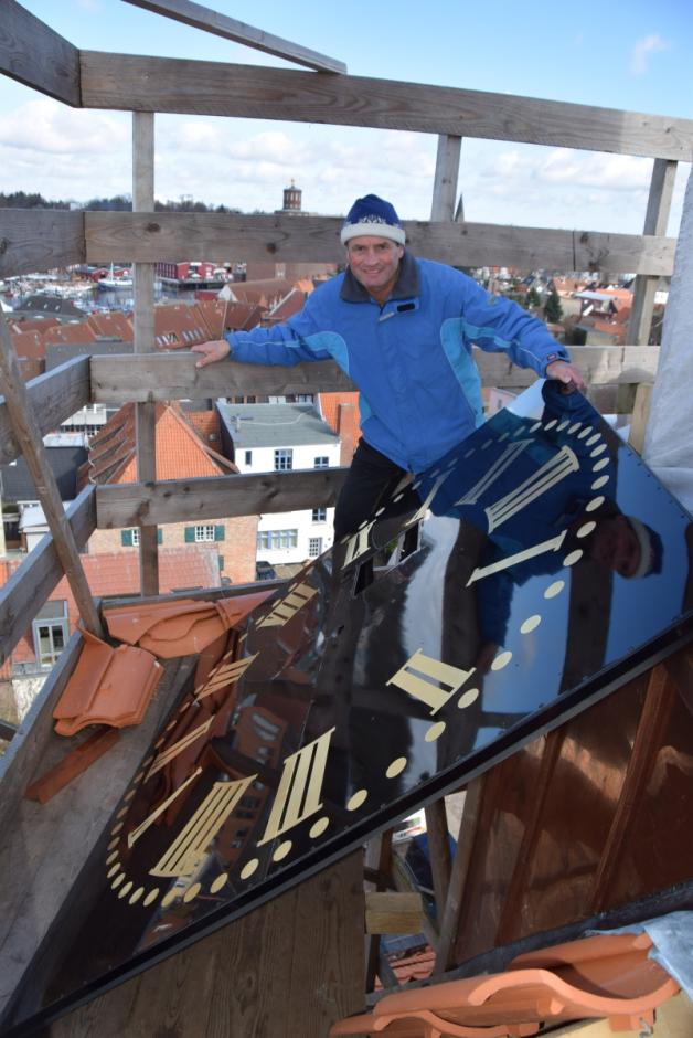 Küster Fritjof Behrens mit einem der neuen Ziffernblätter auf dem Baugerüst des Dachreiters.