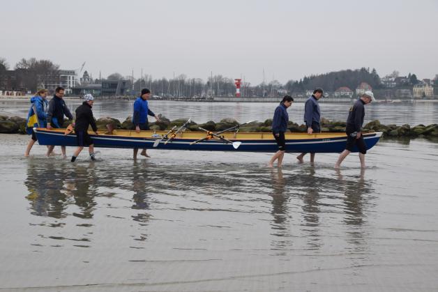 Barfuß in das sechs Grad kalte Ostseewasser – die Ruderer tragen ihr Boot zu Wasser.
