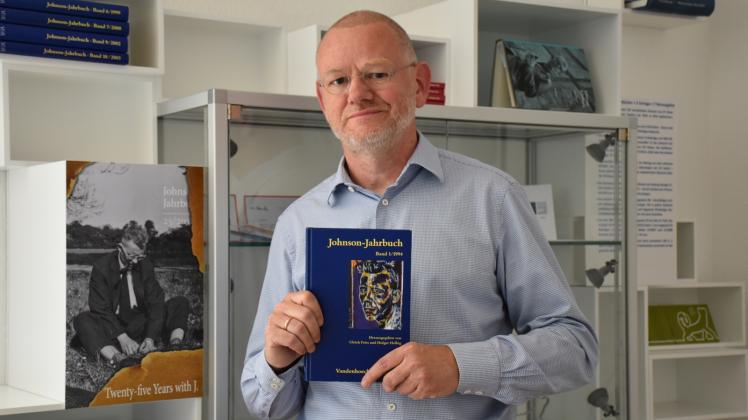 Mit der ersten Ausgabe in der Hand und einer Ansicht des Titelblatts für das 25. Johnson-Jahrbuch, das im Dezember erscheint: Prof. Holger Helbig.