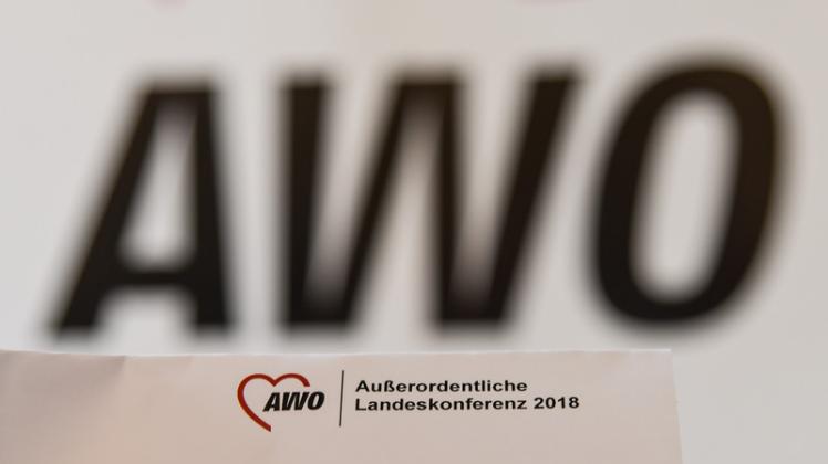Ein Zettel wird bei einer außerordentlichen Landesdelegiertenkonferenz der Arbeiterwohlfahrt (AWO) wird vor ein Logo der AWO gehalten.