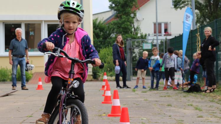 Um die Hütchen und über die Wippe: Vorschülerin Greta Jürß durchfährt den Fahrrad- und Roller-Parcours der Verkehrswacht Güstrow und Umgebung sicher. 