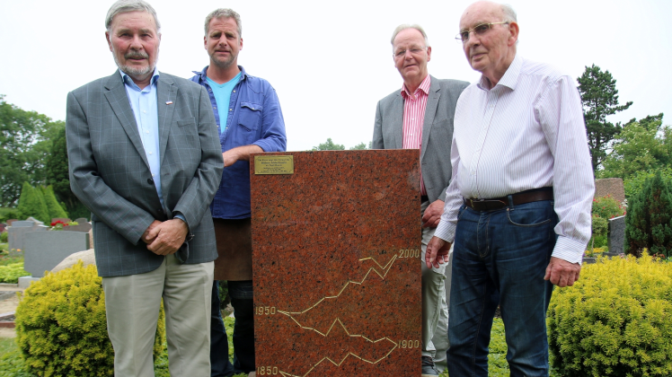 Die Wasserstandskurve dient als Mahnmal auf der Rückseite des Grabsteins von Andreas Busch: (v. l.) Hans-Harro Hansen (Heimatverein Nordstrand), Roman Timme (Steinbildhauer), Frerk Jensen (LKN) und Drees Busch (Enkel des Forschers).