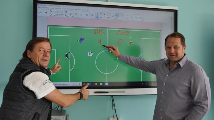 An den Displays der Generation 4.0 können zwei Personen gleichzeitig arbeiten – Schulleiter Thilo Kreimer (r.) und Torsten  Neik zeigen den deutschen Fußballern, wie es geht. 
