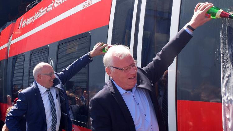 Oberbürgermeister Roland Methling (parteilos, l.) und Dr. Joachim Trettin hatten sichtlich Spaß bei der Sekttaufe der Rostocker Jubiläumsbahn.