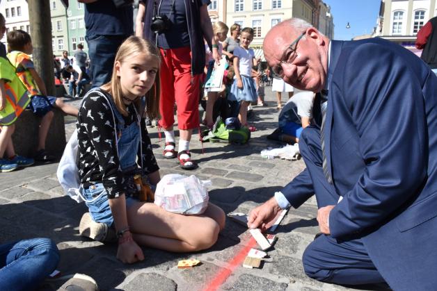 Oberbürgermeister Roland Methling (parteilos) hilft Schülerin Katrine beim Legen der Schachteln. Er hatte mit Ministerpräsidentin Manuela Schwesig auch je ein Mini-Giebelhaus gestaltet.