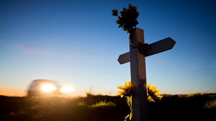 Ein Kreuz und Blumen zur Erinnerung an einen Verkehrstoten 