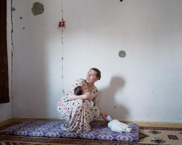 Eine Mutter kümmert sich in einem beschossenen Haus um ihre beiden Kinder. 
