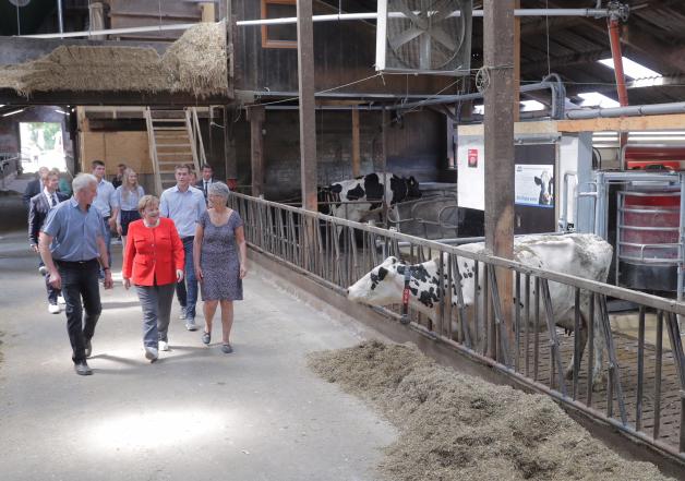 Milchbäuerin Ursula Trede forderte Angela Merkel (M.) dazu auf, sich ein Bild von ihrem Milchviehbetrieb zu machen.