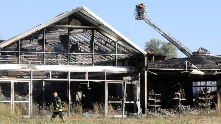 Die Feuerwehr lässt zwei Lagerhallen kontrolliert abbrennen, nachdem ein Feuer von einer Lagerhalle für Kleinfeuerwerk auf eine benachbarte Halle übergriff, in dem u.a. Möbel gelagert wurden.