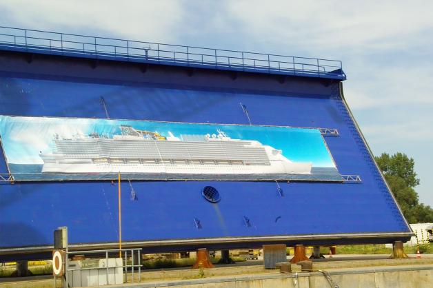 Auf einem riesigen Transparent am Warnemünder Standort von MV Werften bereits zu bewundern: Ein Mega-Kreuzfahrtschiff der  Global Class, von denen zunächst zwei auf den Werften in Warnemünde und Wismar gebaut werden sollen.