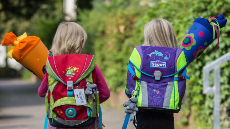 Zwei Mädchen gehen mit Schultüten zu ihrem ersten Schultag.
